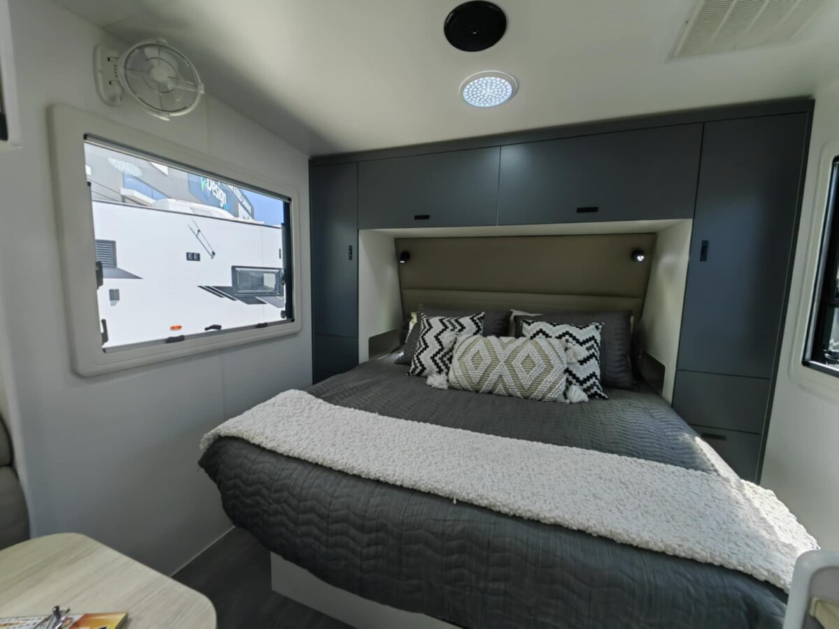 Caravan queen bed surrounded by green cabinets