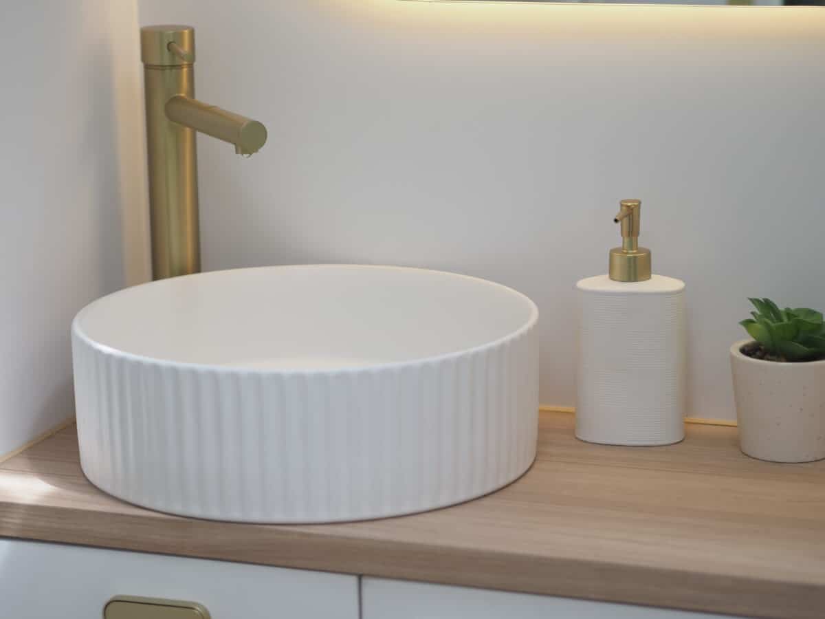 A fluted circular sink with brushed gold tapware
