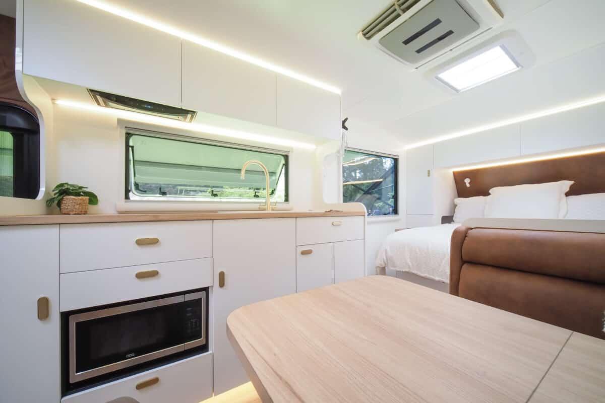 Lots of cabinetry. This view of the the Grand Caravans 2025 interior shows expansive white drawers with an embedded microwave taken from the view of the dinette lounge