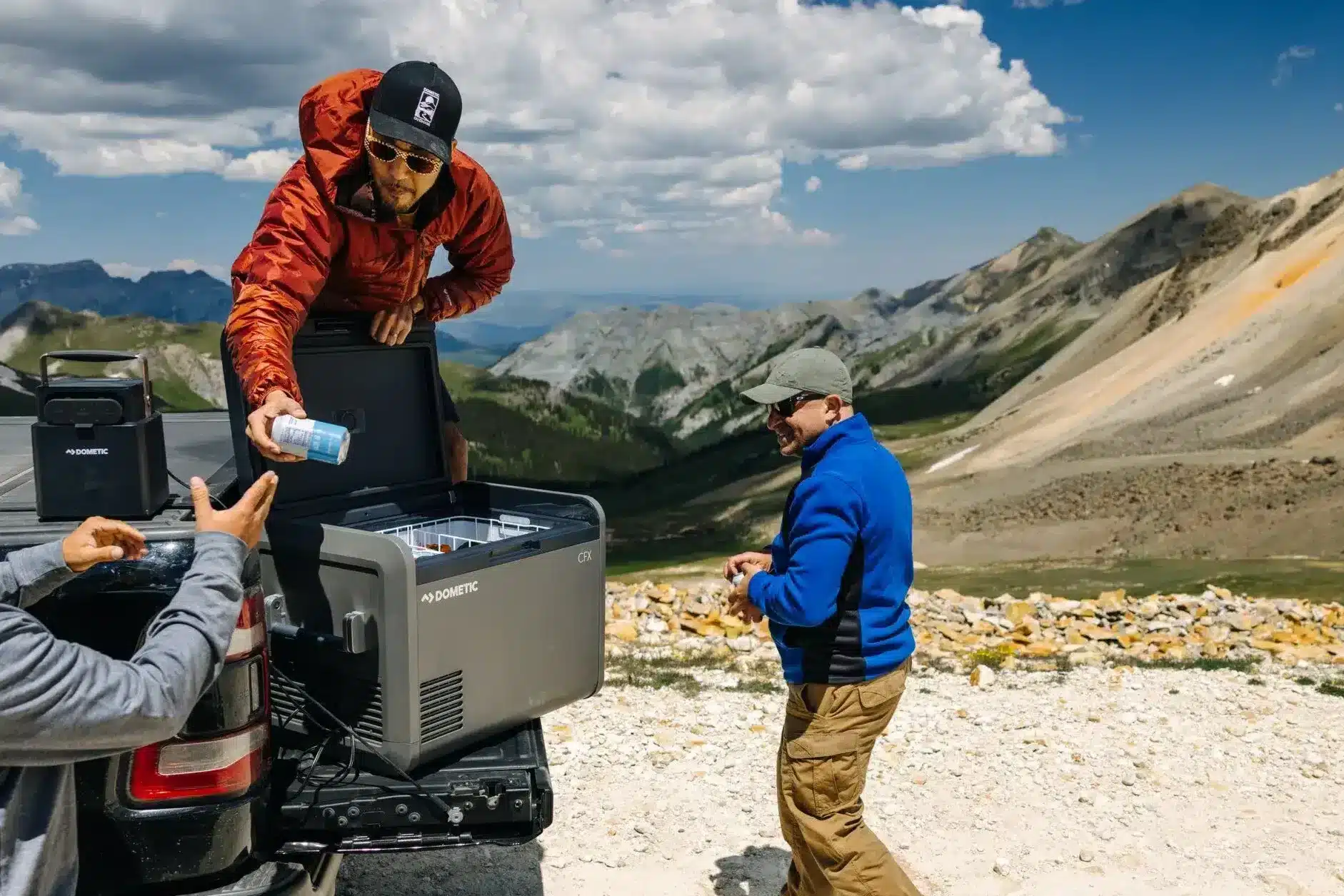 man getting beers out of portable fridge in beautiful landscape