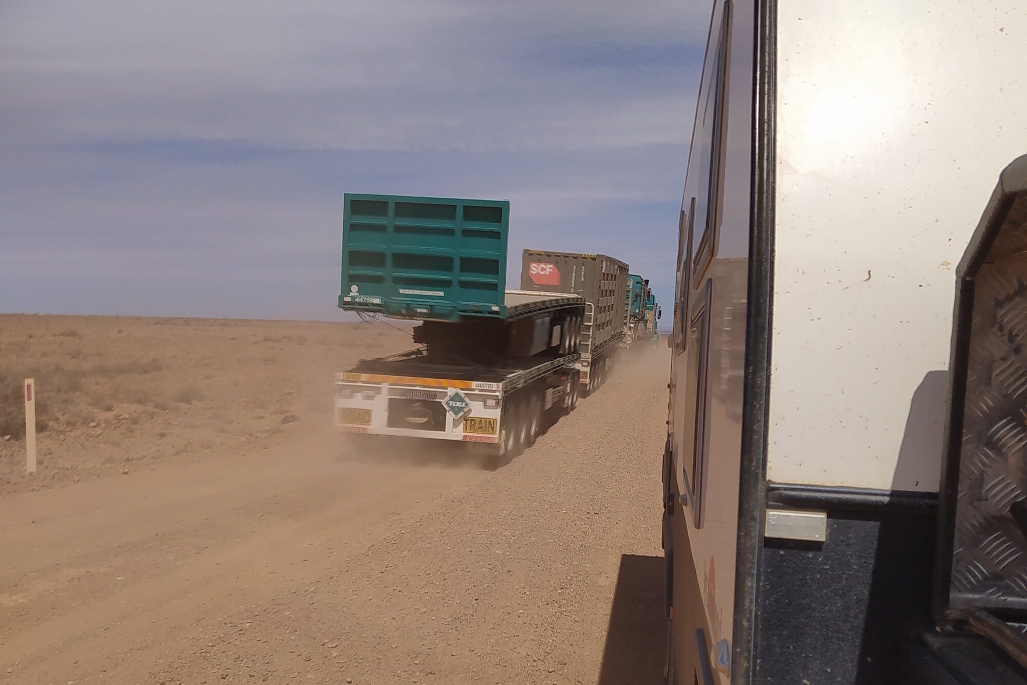 Side view of a caravan with a road train in the other direction having just passed. Dirt roads and off-road touring will increase your fuel usage. Remote TOuring Guide