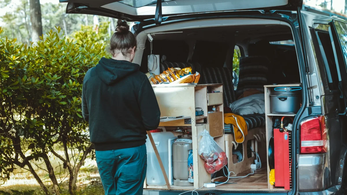 man standing at the back of rv camper contemplating decision