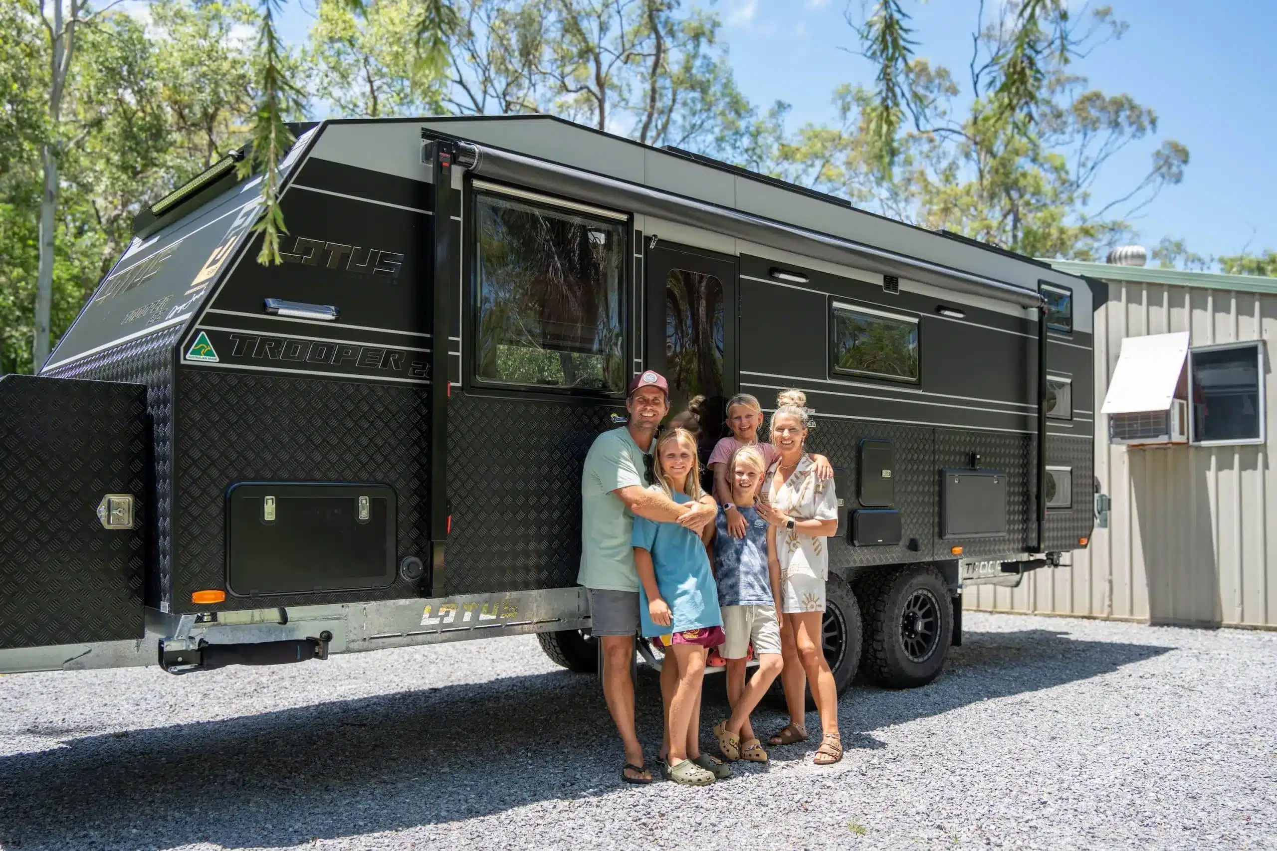 family standing in front of big black caravan