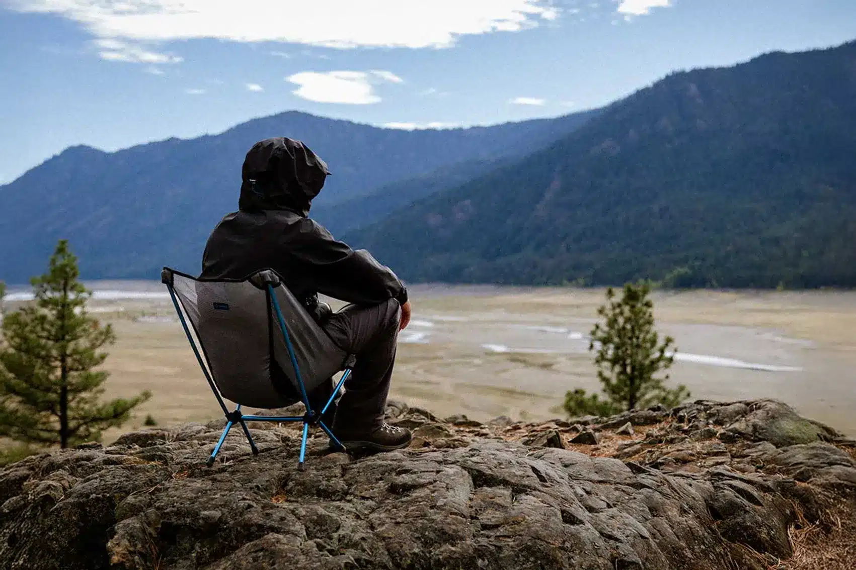 person sitting in chair looking into valley and mountains