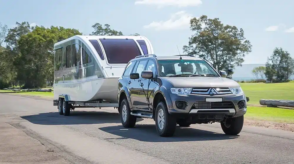 A tow vehicle towing a caravan–boat hybrid on an Australian road, highlighting interest in single multi-use touring setups.