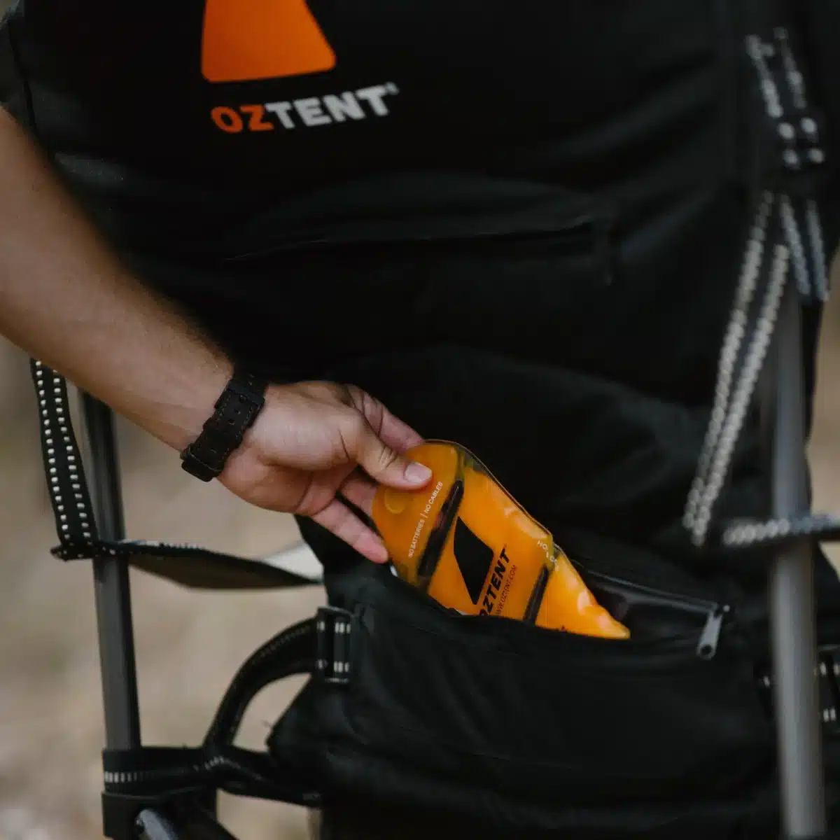 hand reaching into grab orange item from camp chair