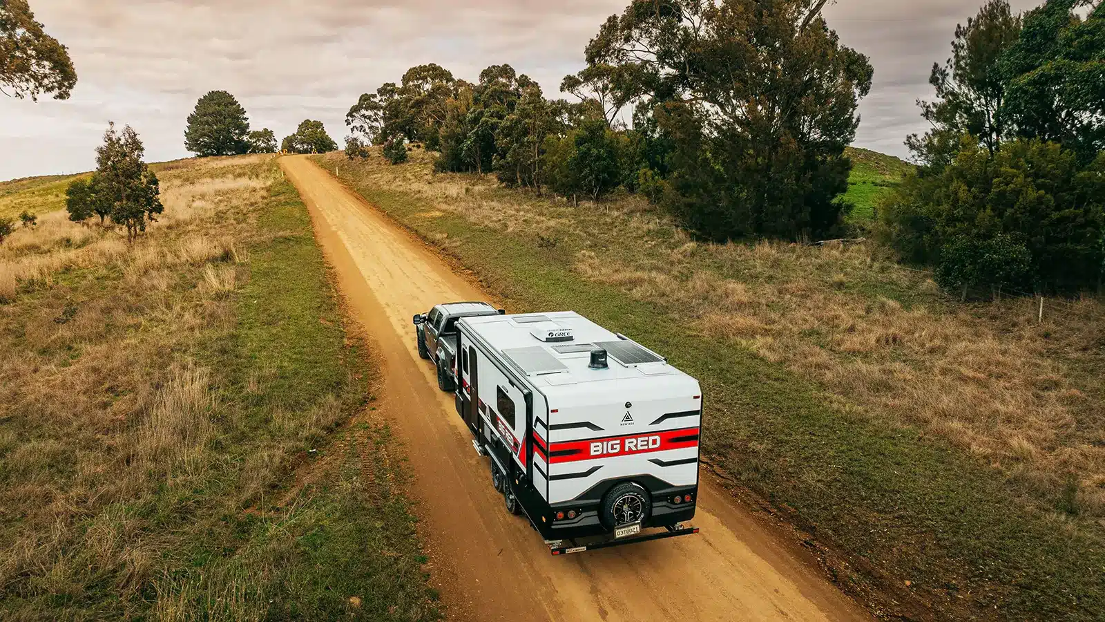 Caravan being towed along a regional dirt road in Australia during a road trip affordable Easter caravan holidays