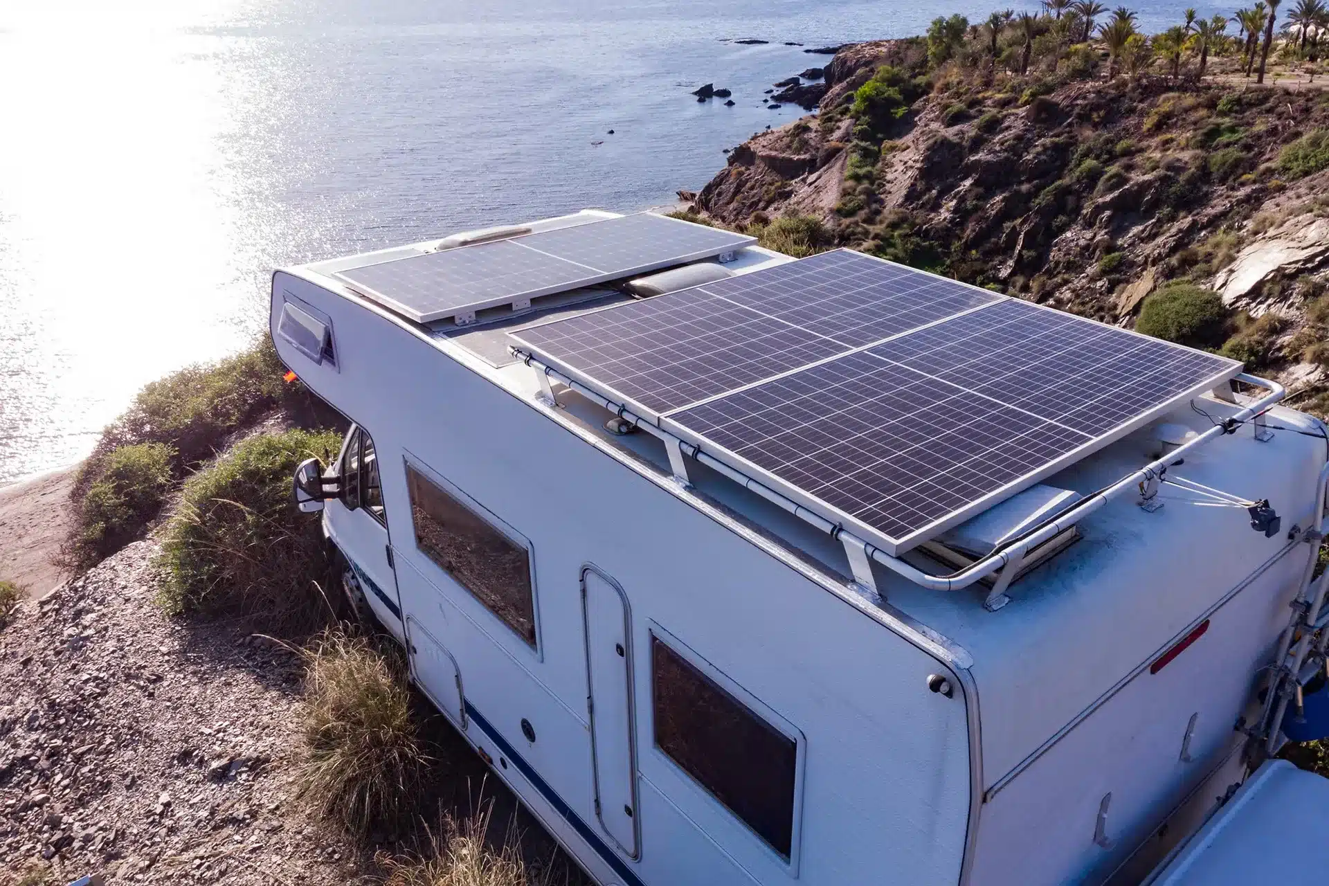 Caravan with rooftop solar panels parked near a coastal cliff while free camping off grid